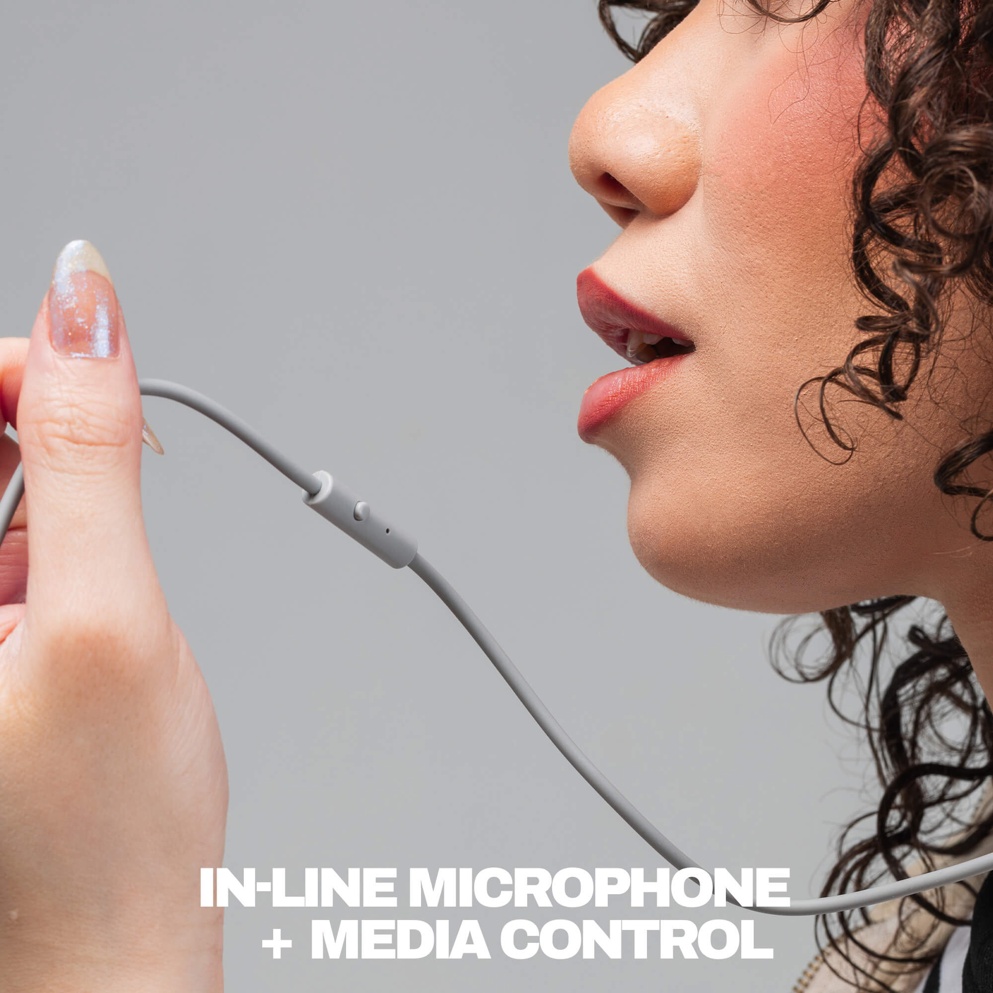 Close-up of a person holding a gray in-line microphone and cable near their mouth, with text at the bottom reading 'IN-LINE MICROPHONE + MEDIA CONTROL' on a light gray background. | Cement
