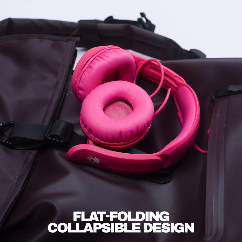 Bright pink over-ear headphones resting on a dark brown waterproof backpack, with the text 'FLAT-FOLDING COLLAPSIBLE DESIGN' at the bottom. | Crazy Pink