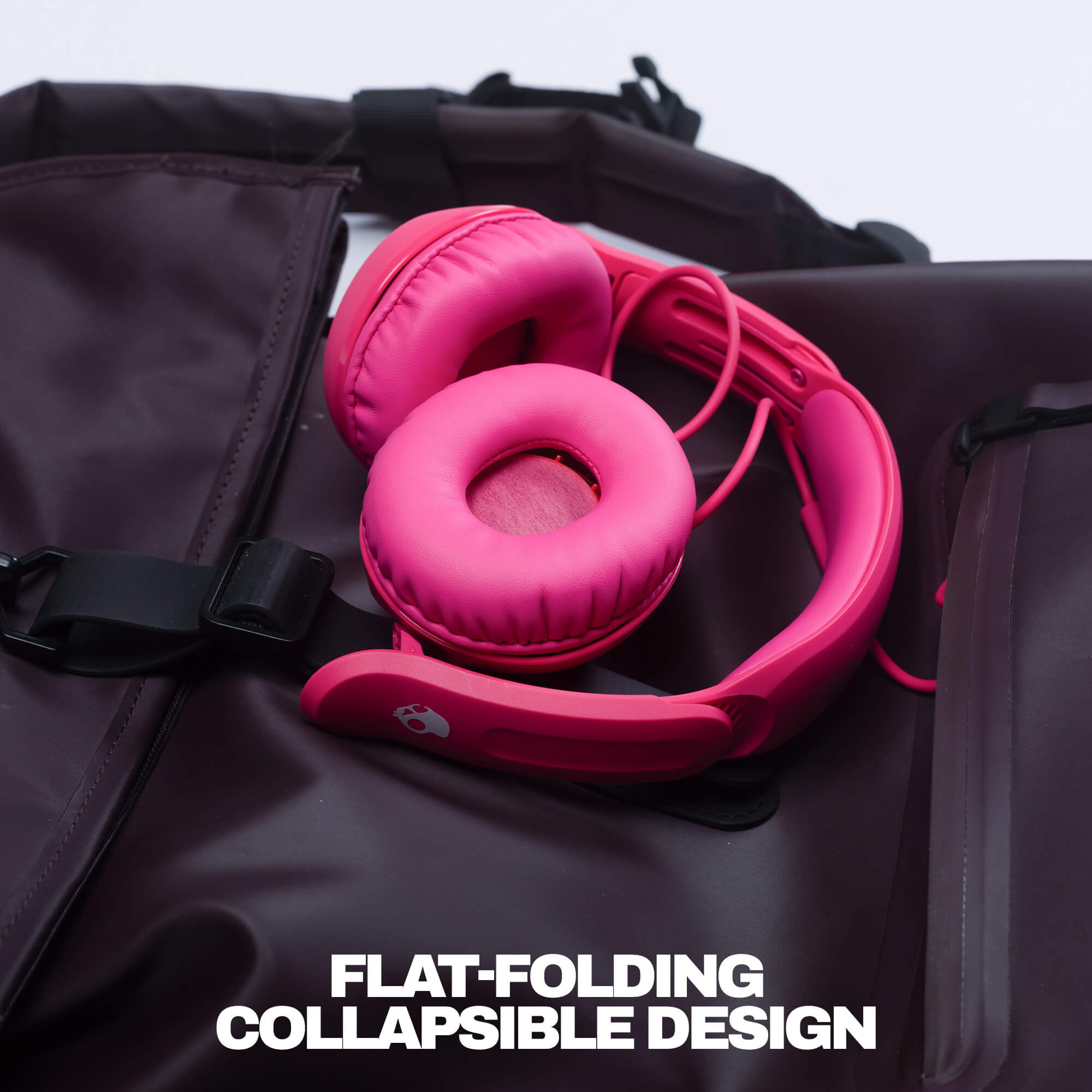 Bright pink over-ear headphones resting on a dark brown waterproof backpack, with the text 'FLAT-FOLDING COLLAPSIBLE DESIGN' at the bottom. | Crazy Pink