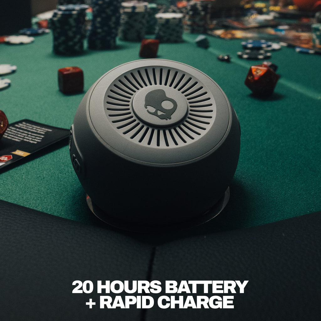 Round electronic device on a gaming table with text about battery life and charging. | Cement
