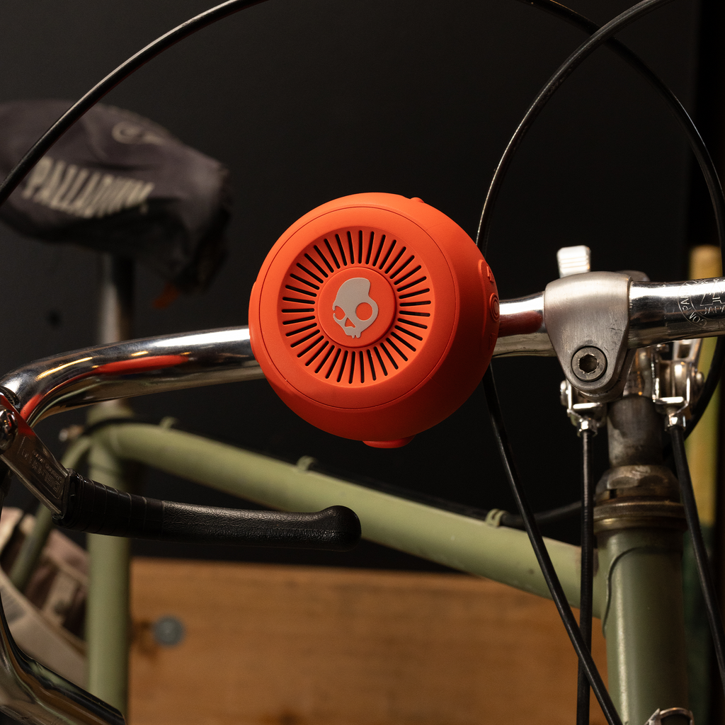 Red speaker attached to a bike handlebar with a blurred background | Plasma