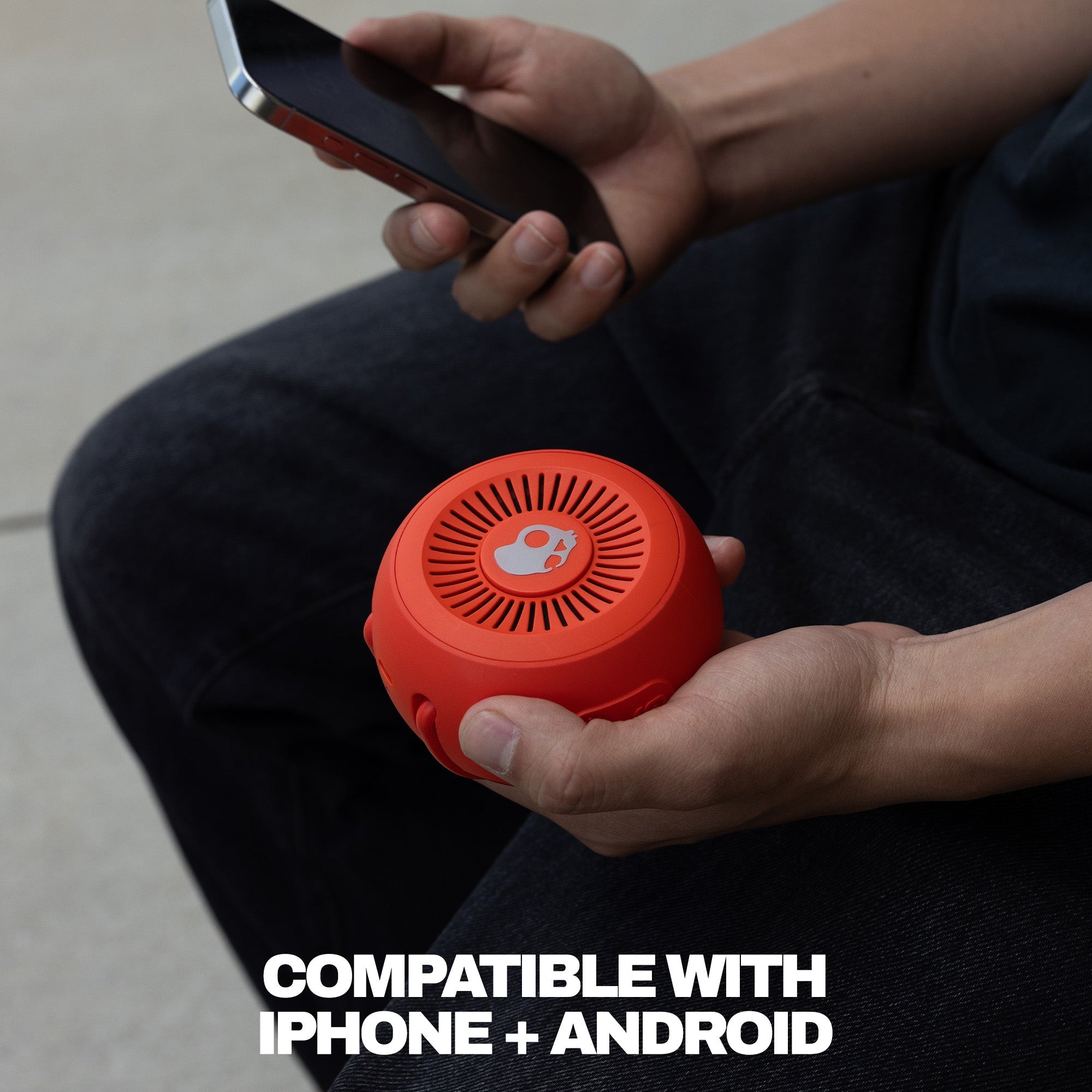 Person holding a red portable speaker and smartphone, with text indicating compatibility with iPhone and Android. | Plasma