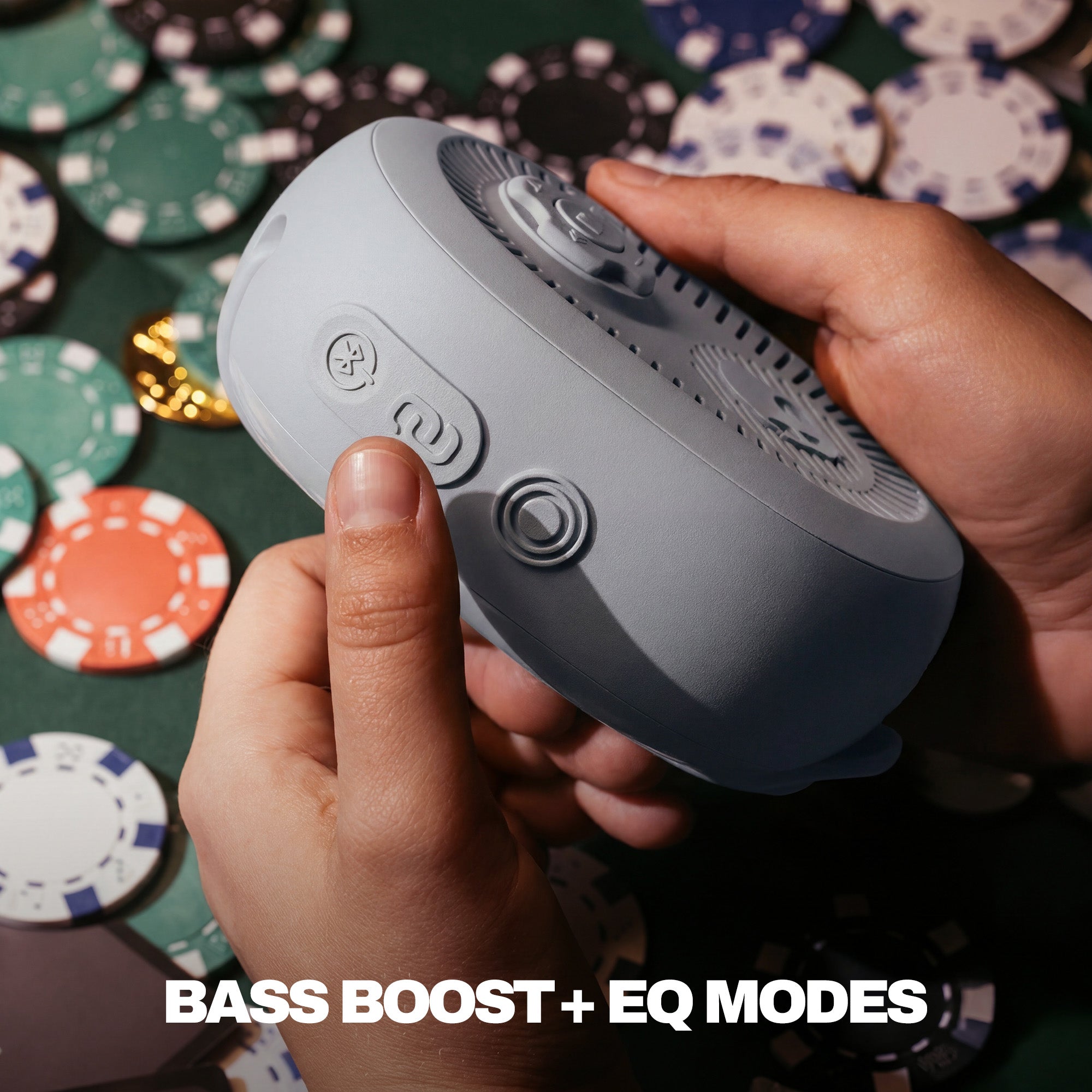 Person holding a gray electronic device with buttons, surrounded by poker chips on a green felt surface. | Cement