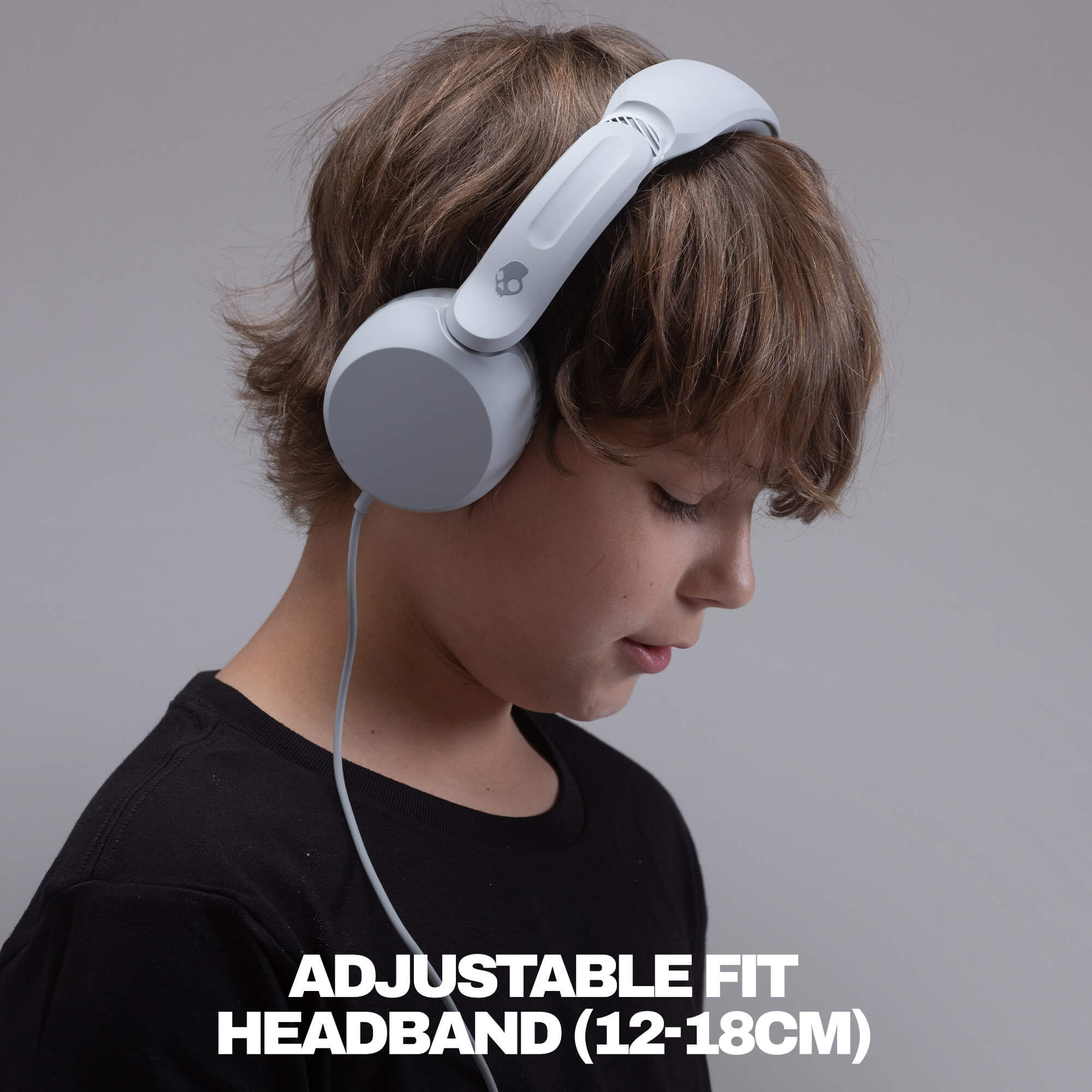 A child wearing light gray over-ear headphones with a white adjustable headband, shown in profile against a plain gray background with the text 'ADJUSTABLE FIT HEADBAND (12-18CM)' at the bottom. | Cement