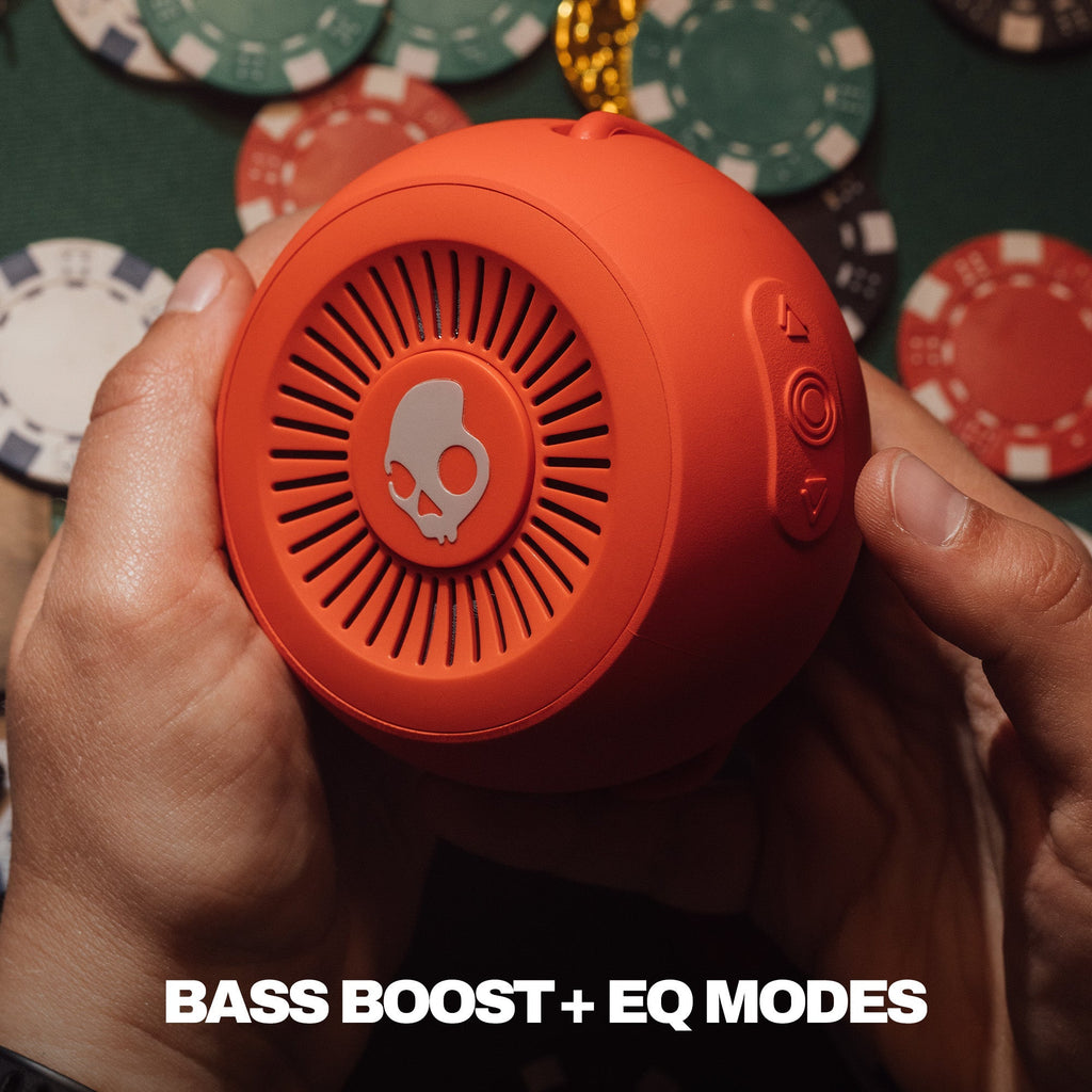 Person holding an orange portable speaker with poker chips in the background | Plasma