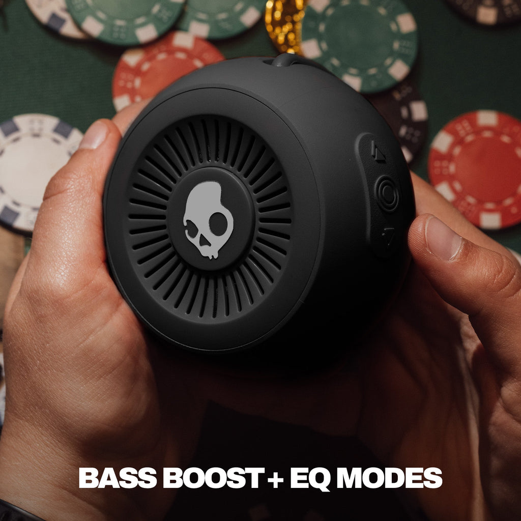 Black skull-themed speaker held by a hand with poker chips in the background | True Black