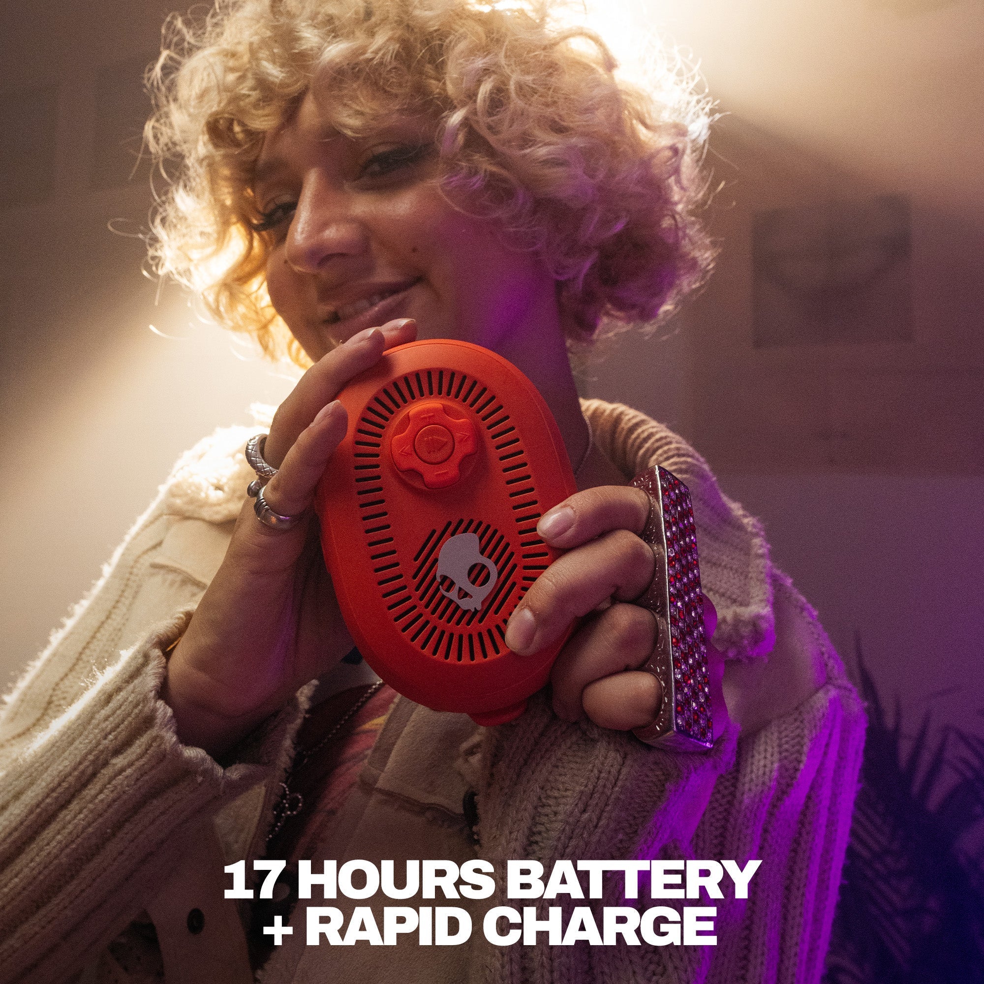 Person holding a red device with text about battery life and charging speed. | Plasma