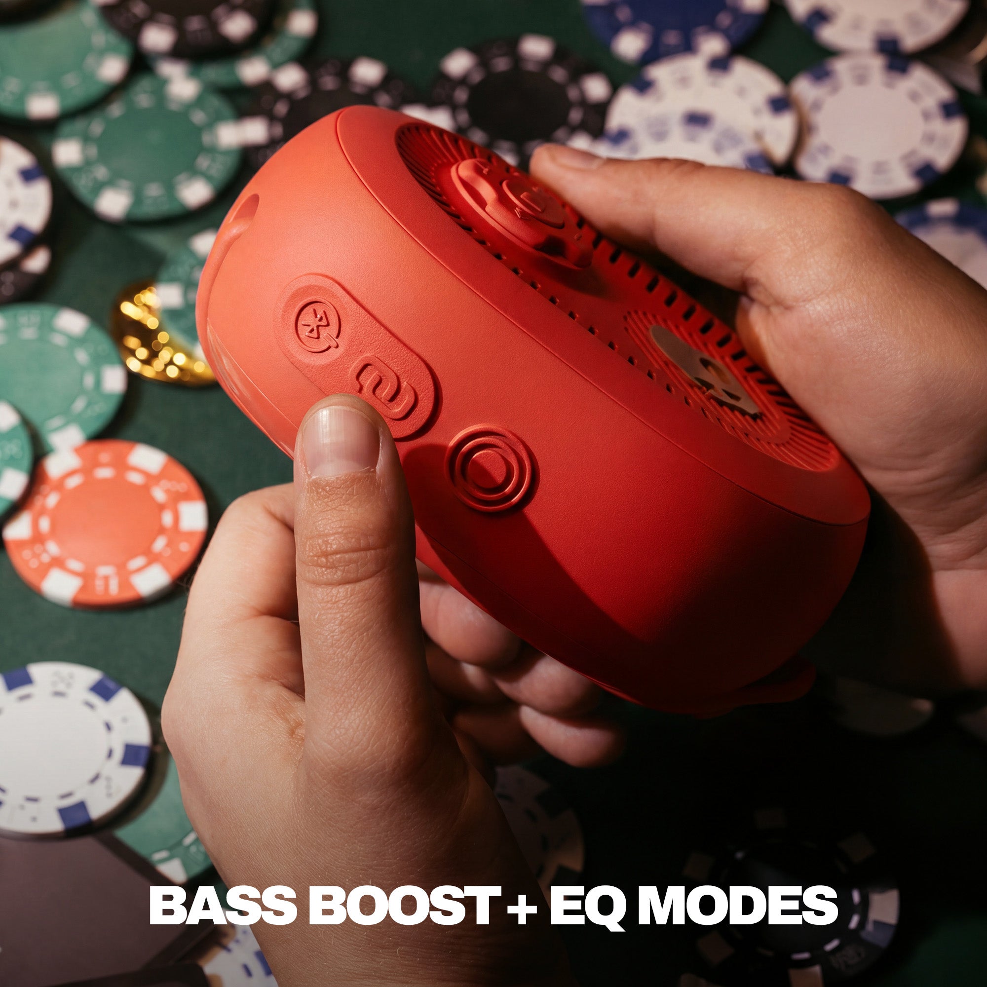 Red portable speaker held by a hand with poker chips in the background | Plasma