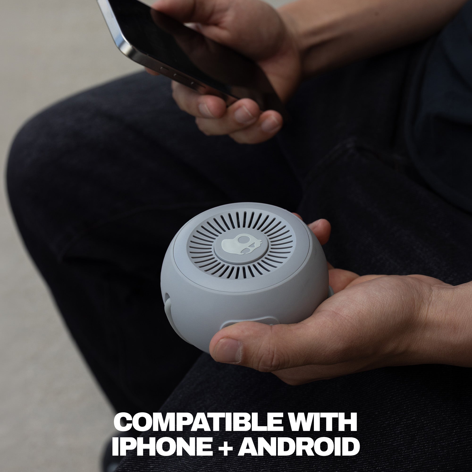 Person holding a small white device with text indicating compatibility with iPhone and Android. | Cement