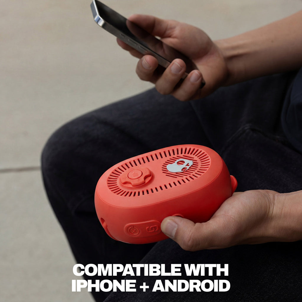 Person holding a red device and a smartphone with text 'Compatible with iPhone + Android' on a neutral background. | Plasma